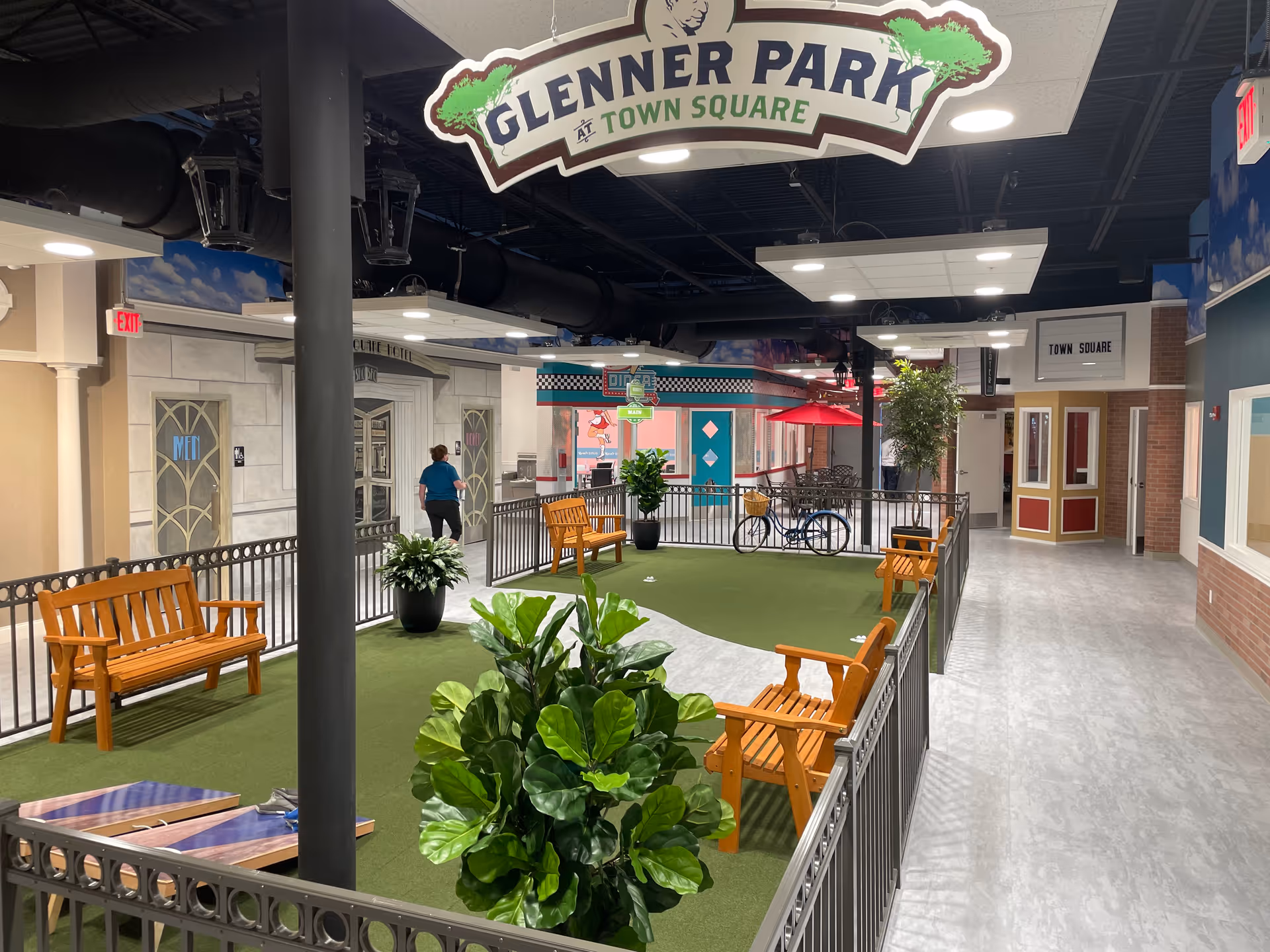 Indoor atrium at Town Square with benches, artificial lawn, plants, and signage.