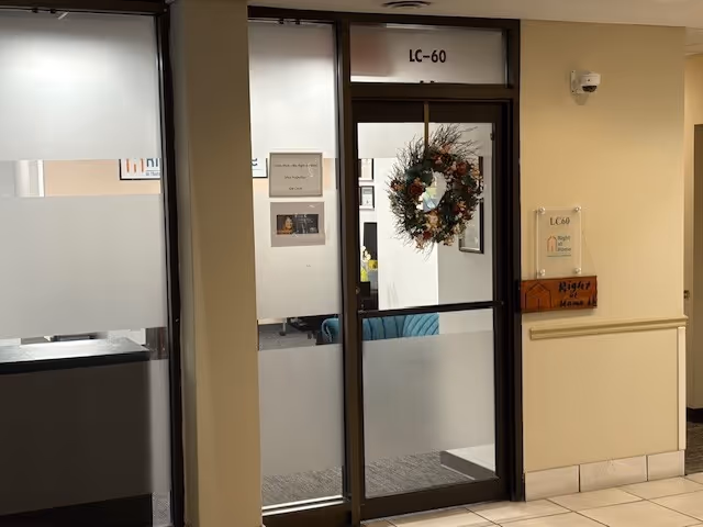 Interior facility entrance with glass doors, a hanging wreath, and wall signs.