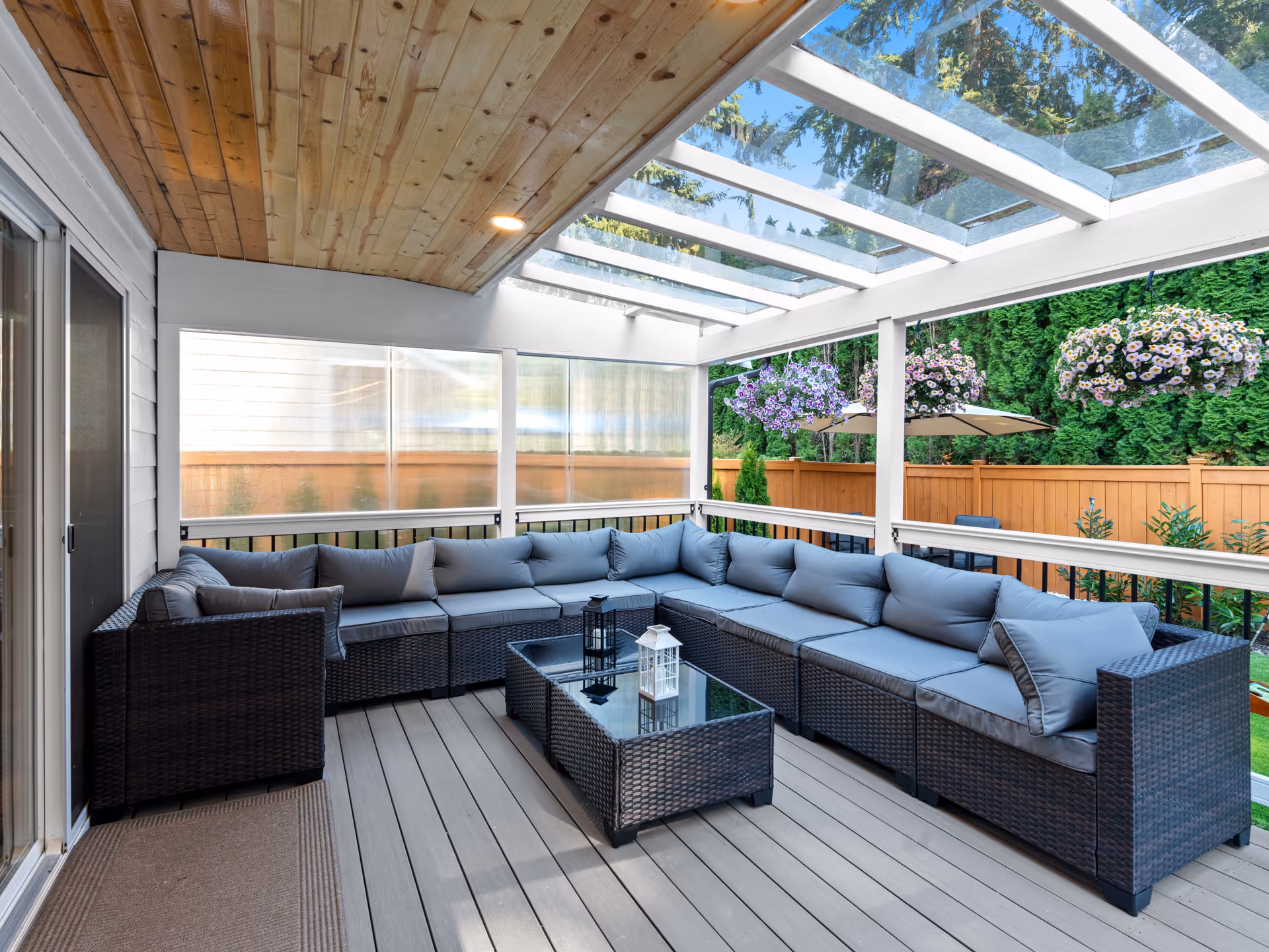 Covered outdoor patio with L-shaped wicker seating, cushions, and a glass coffee table.