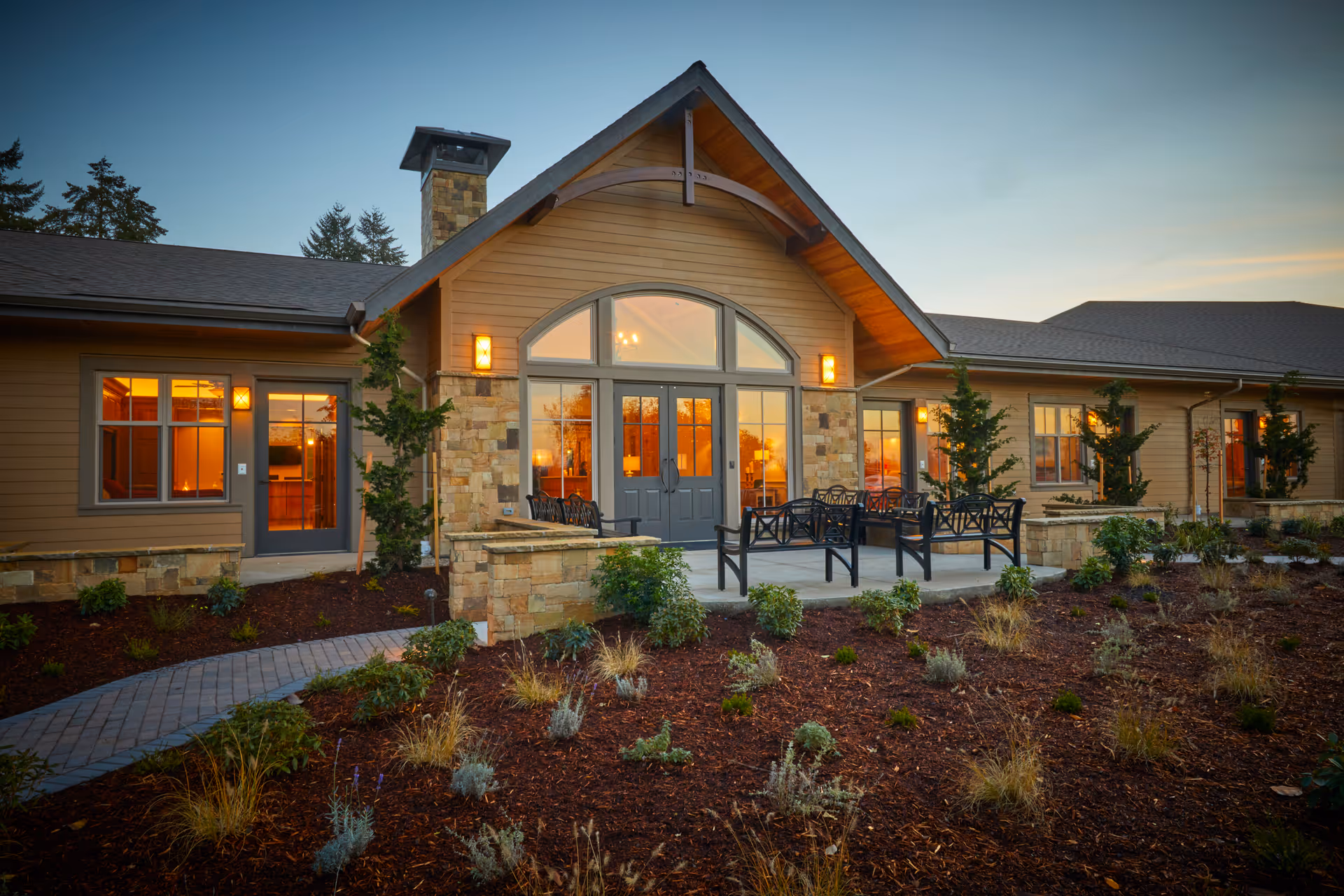 Exterior view of a single-story facility with a stone facade and outdoor seating.