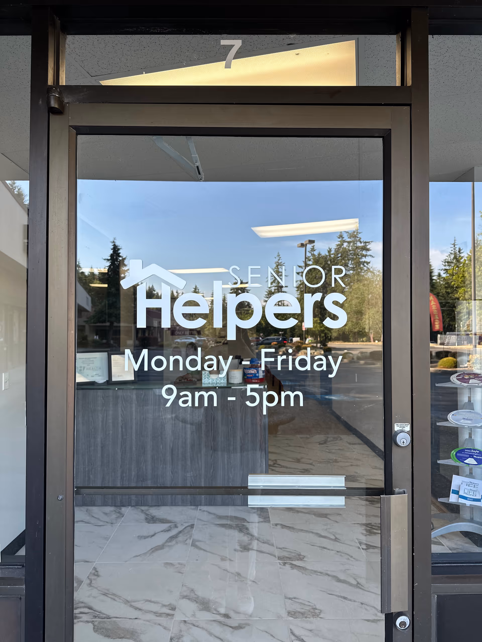 Entrance glass door displays Senior Helpers logo and hours with a marble lobby floor.