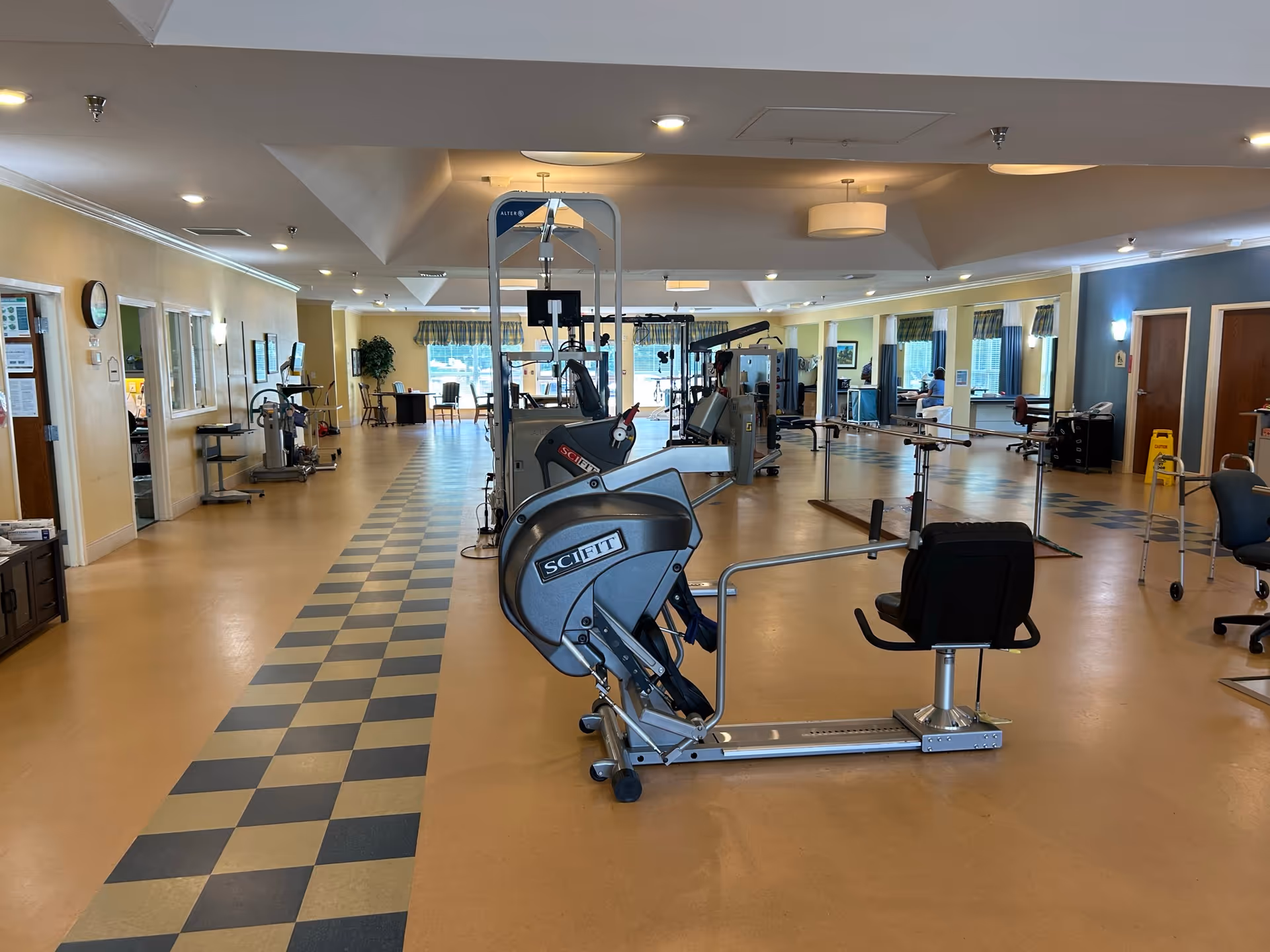 Indoor senior living gym with exercise machines and stationary bikes in a spacious room.