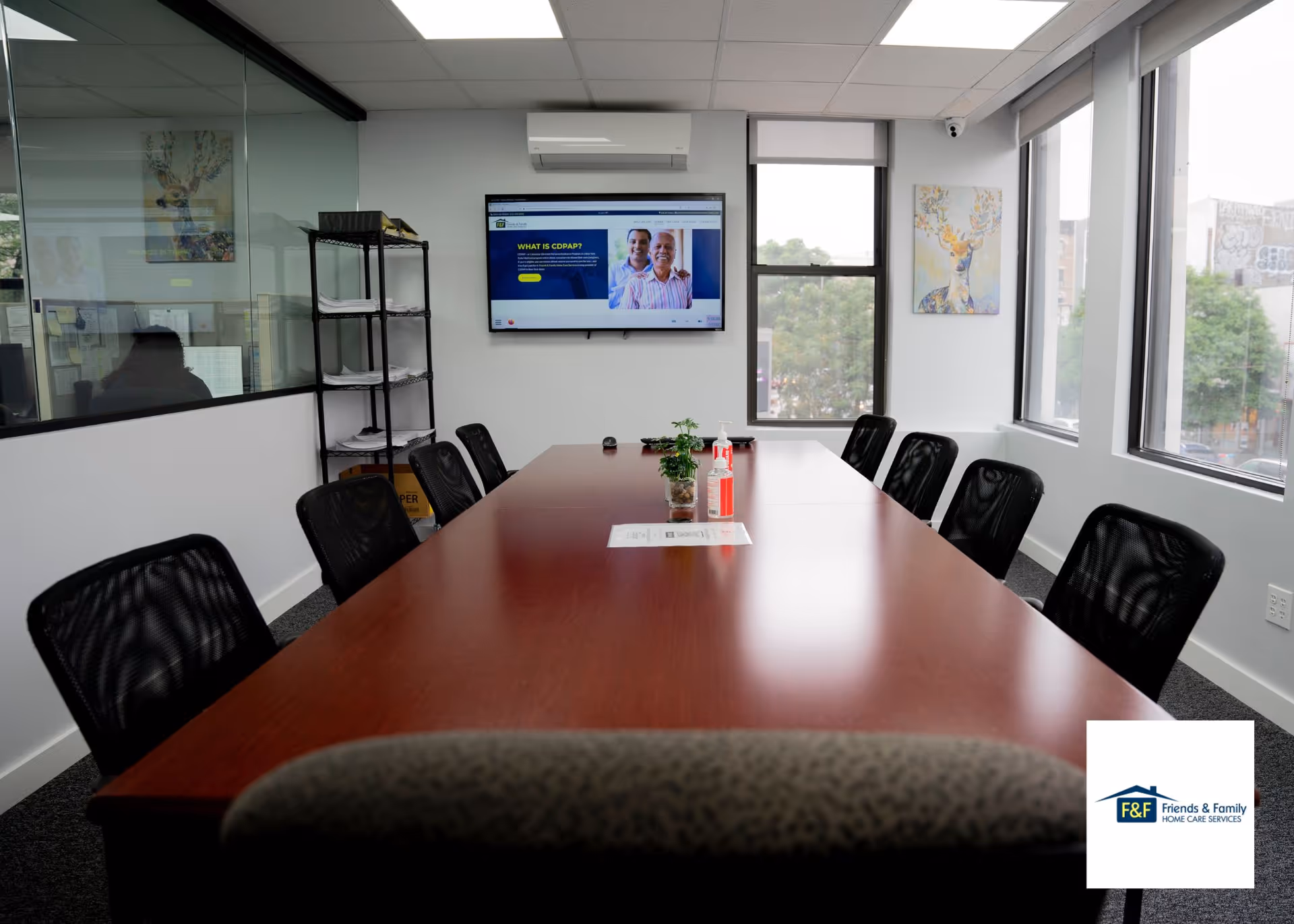 Meeting room with a long table, chairs, a wall screen, and logo.