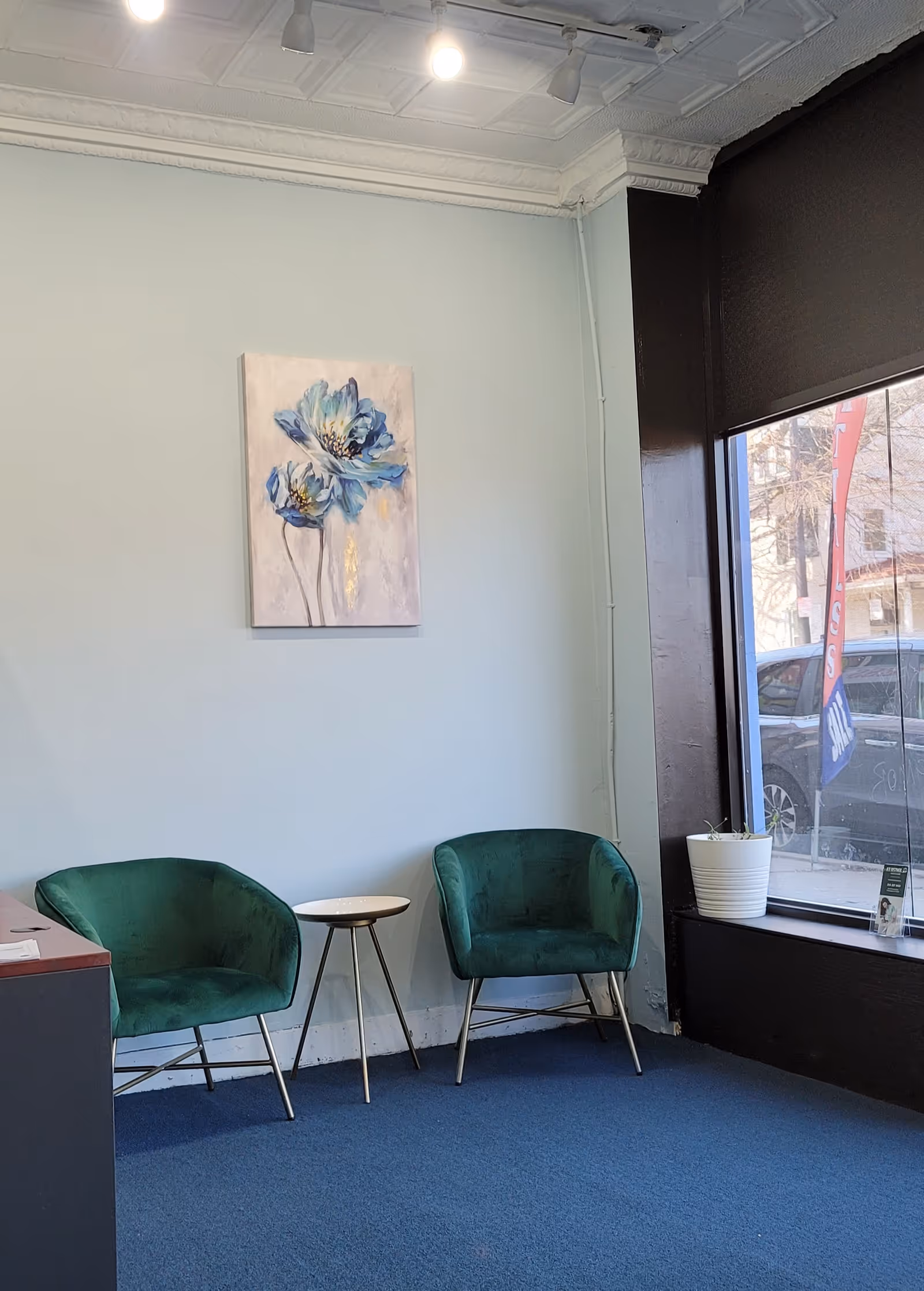Small lobby seating area with two green chairs, a white table, and blue carpet.