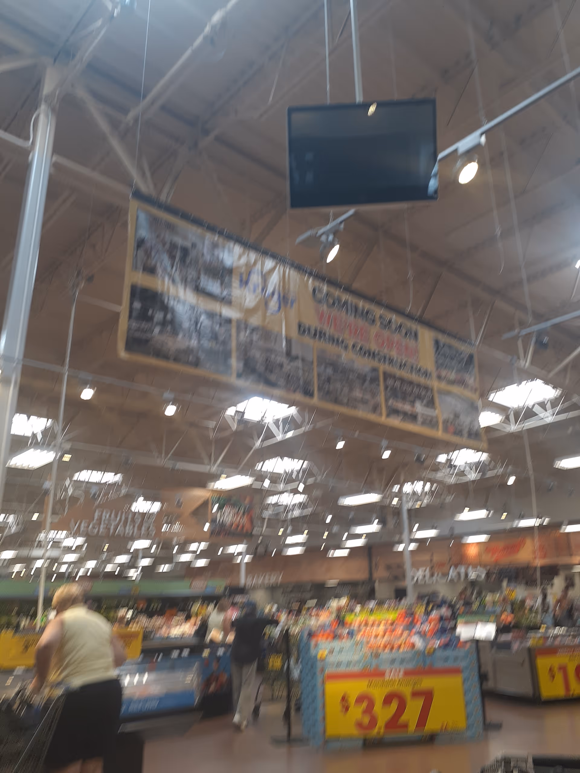 Inside a Kroger grocery store, shoppers browse produce aisles under bright lights.
