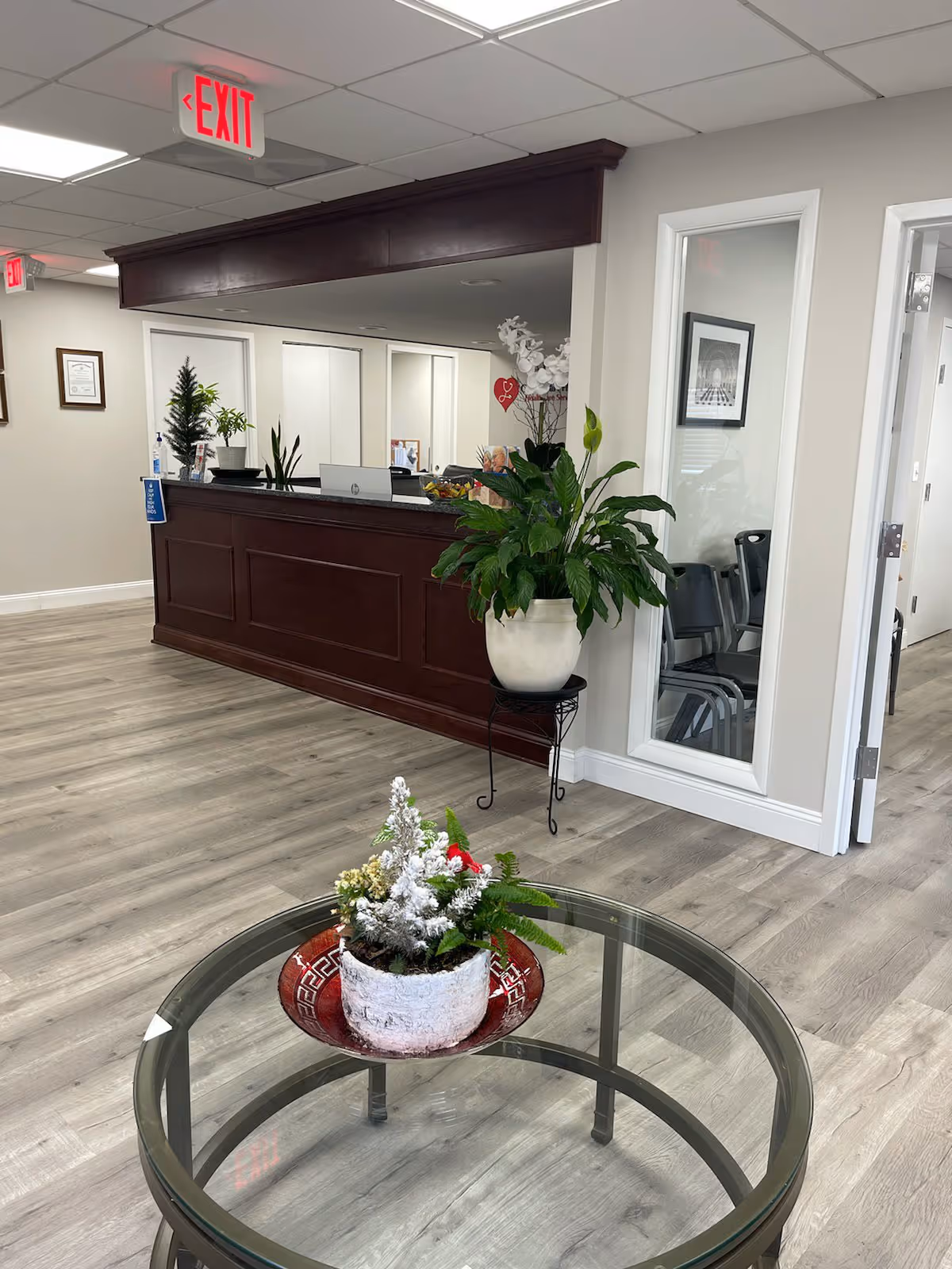 Interior of a senior living facility with a dark reception desk, plants, and a glass table.