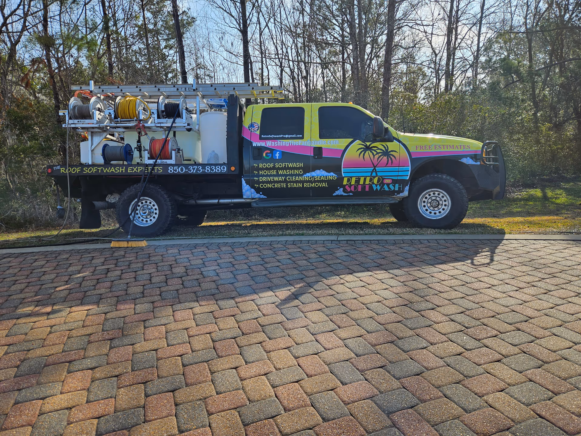 Bright, multicolor service truck with hoses and equipment on a brick driveway.