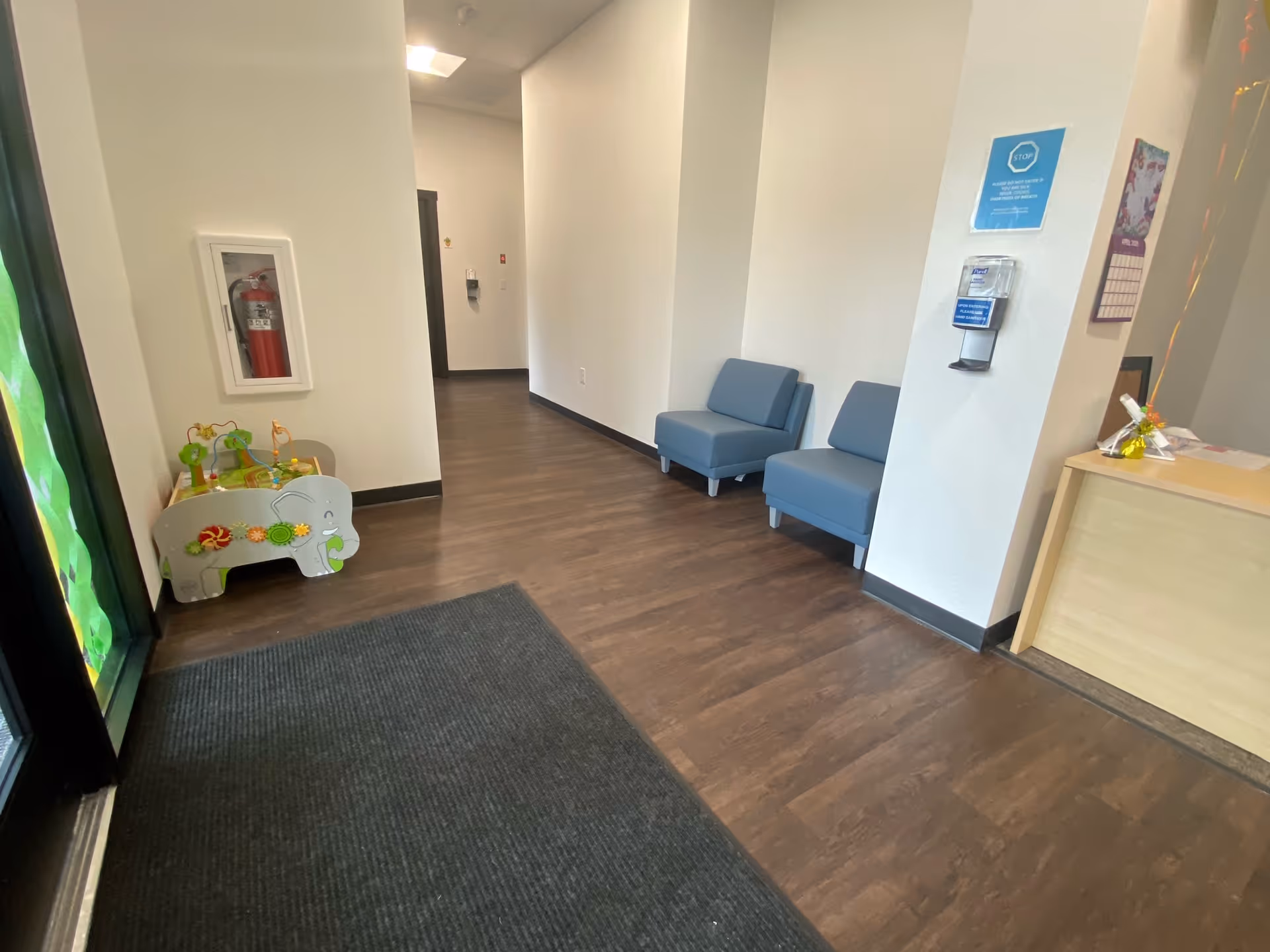 Interior hallway with blue seating and a children's play area near the entrance.