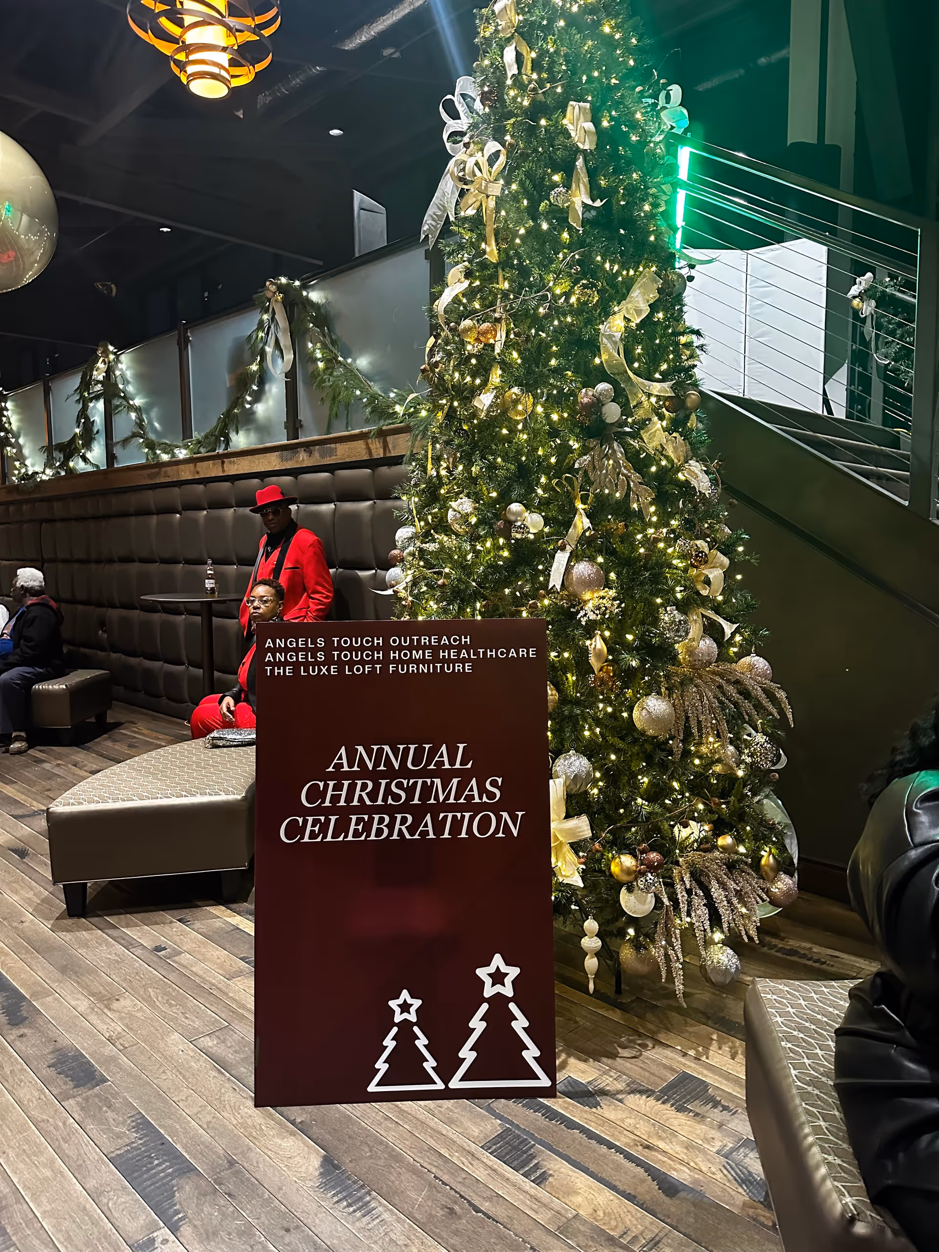 A large Christmas tree and celebration sign are displayed in a modern interior lobby.