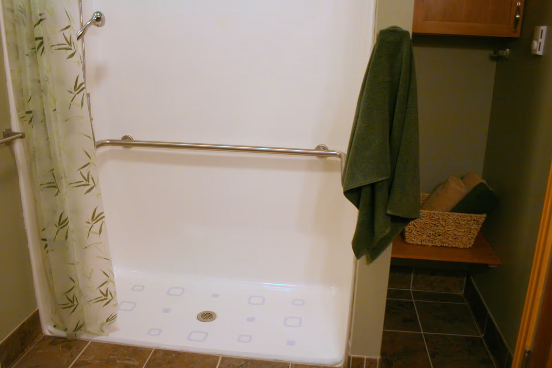 Walk-in shower with grab bar, curtain, and a small storage corner.