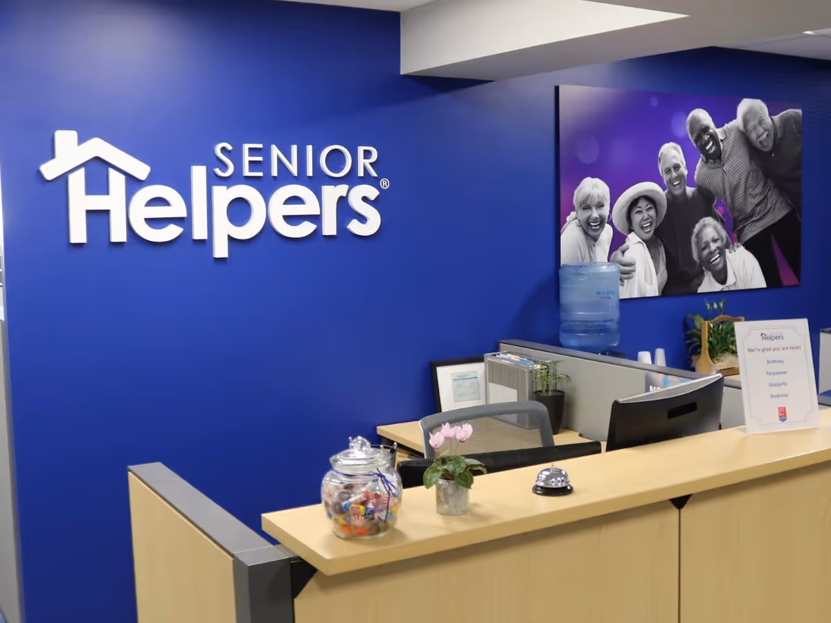 Blue reception area with Senior Helpers logo and a front desk in a lobby.