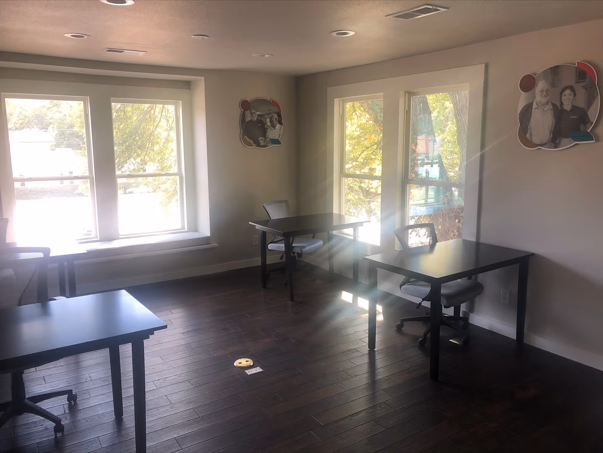 Interior room with several desks and chairs by large windows.