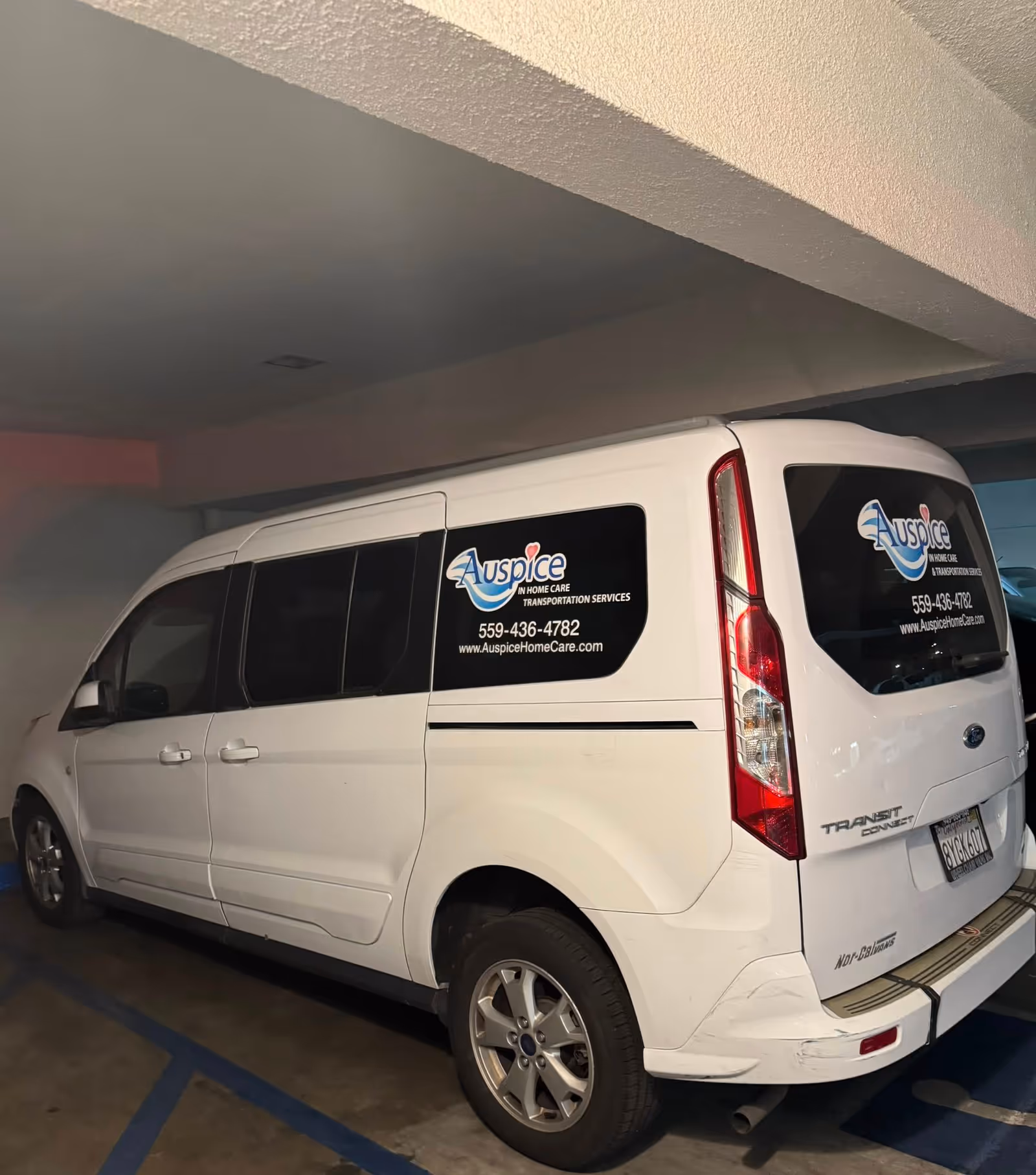 White Auspice van with branding parked in a dim indoor parking garage