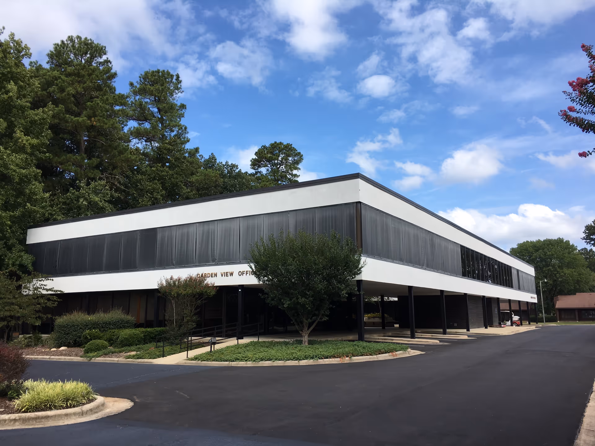 Modern, two-story office-style building with black-and-white façade, surrounded by trees and a parking lot.