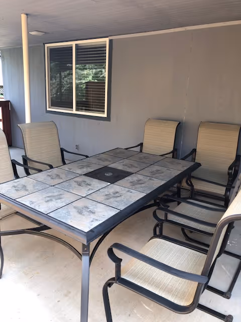 Outdoor covered patio with a tiled table and beige dining chairs.