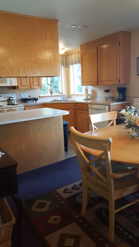Wooden cabinets, a kitchen island, and a round dining table in a bright, cozy kitchen.