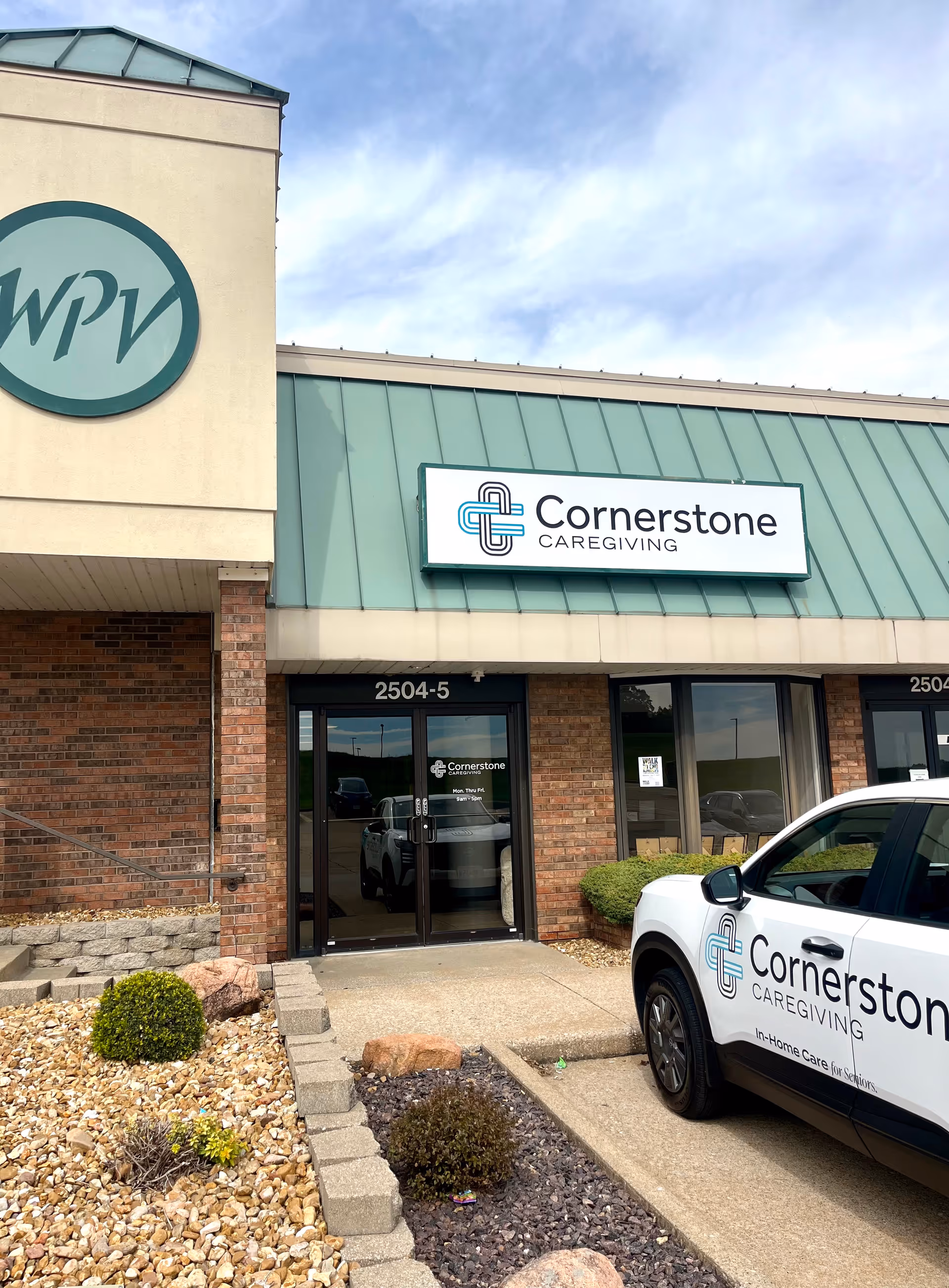 Front exterior of Cornerstone Caregiving building with signage and a parked car.