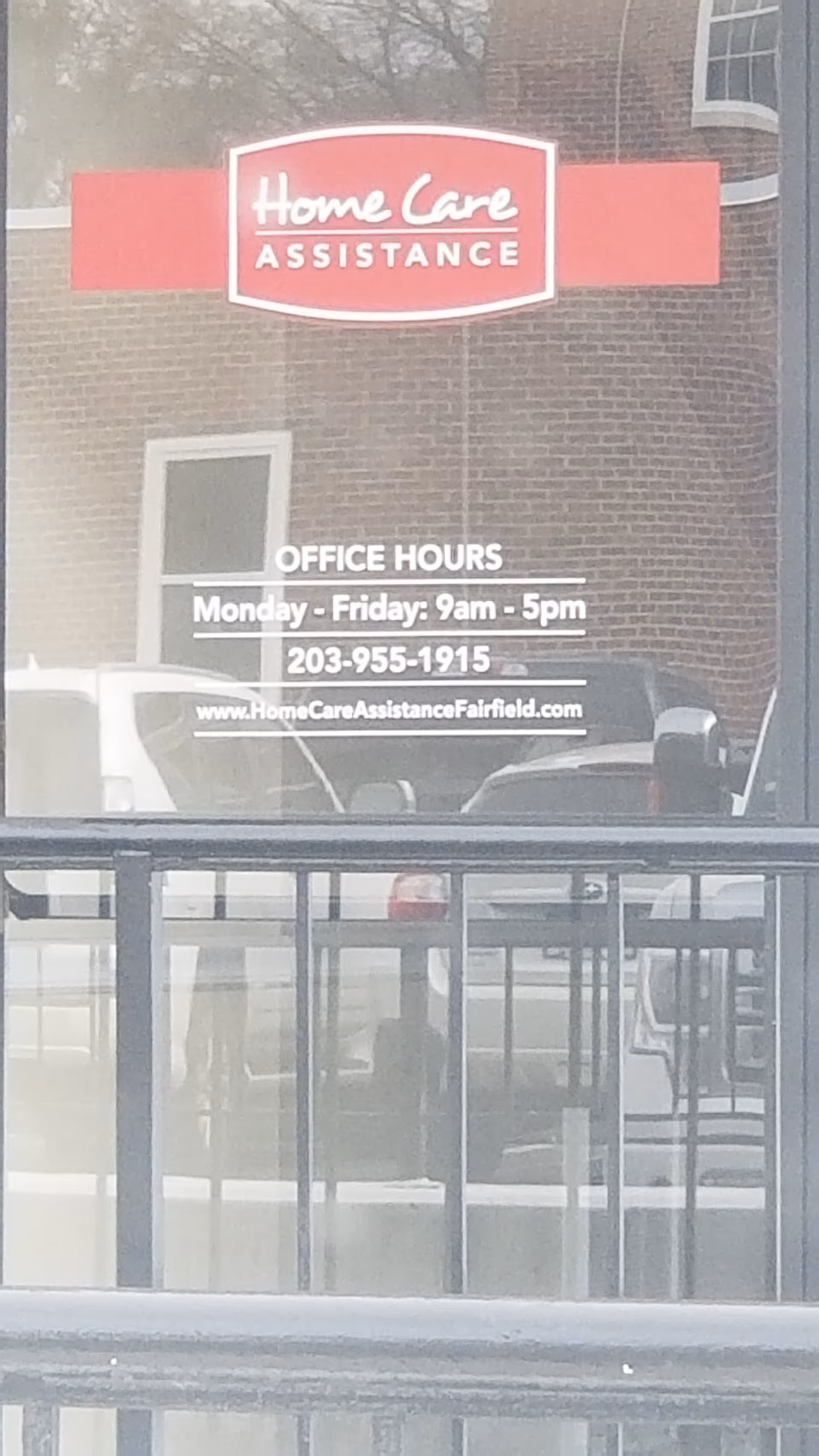 Exterior storefront window sign for Home Care Assistance showing office hours.