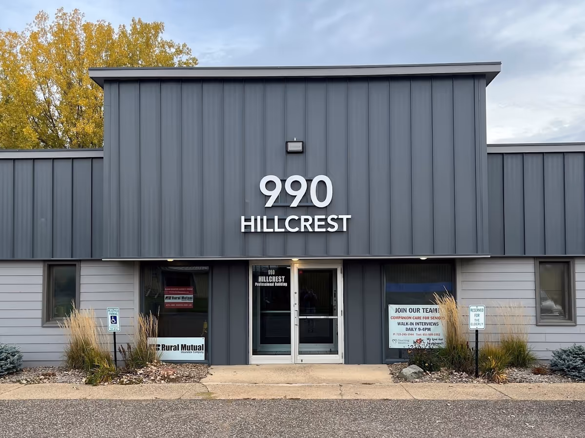 Gray modern building facade with large 990 Hillcrest sign and glass entrance.