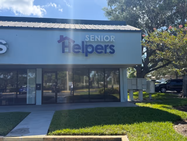 Exterior of Senior Helpers storefront with glass doors and a small front lawn.