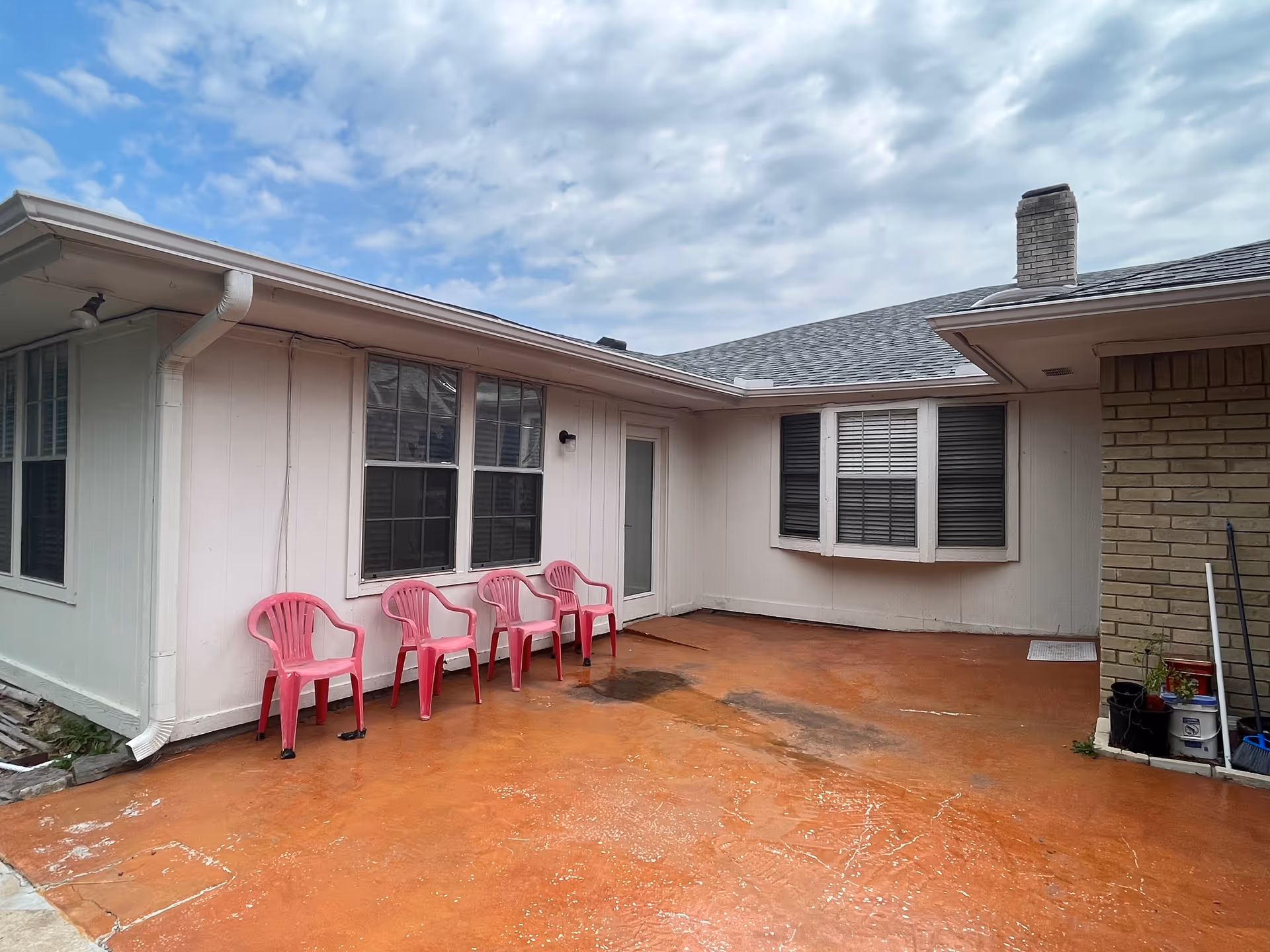 Back courtyard of Sunny Oak Care Home LLC with pink plastic chairs along the wall.