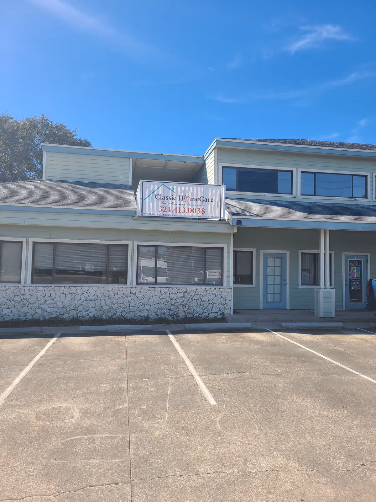 Exterior view of Classic HomeCare facility with banner sign, large windows, and empty parking lot.