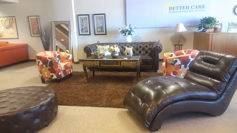 Lobby-style living room with leather sofas, colorful chairs, coffee table, and plants.