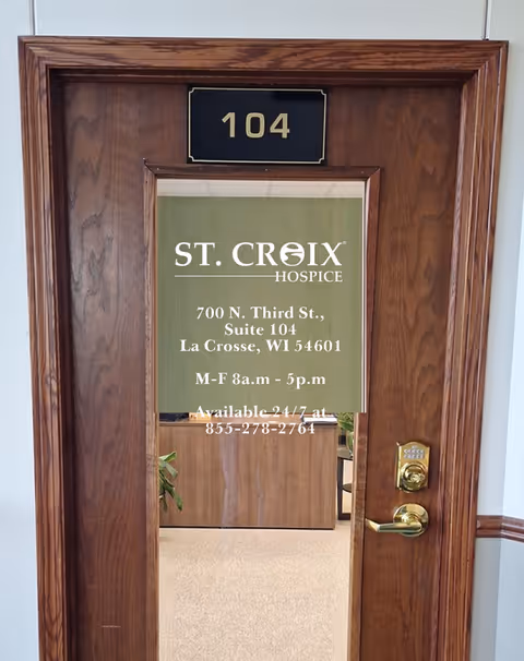 A wooden door with room number 104 and a glass panel displaying St. Croix Hospice sign.