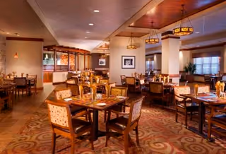 Bright dining room with multiple tables, chairs, and warm ceiling lights.