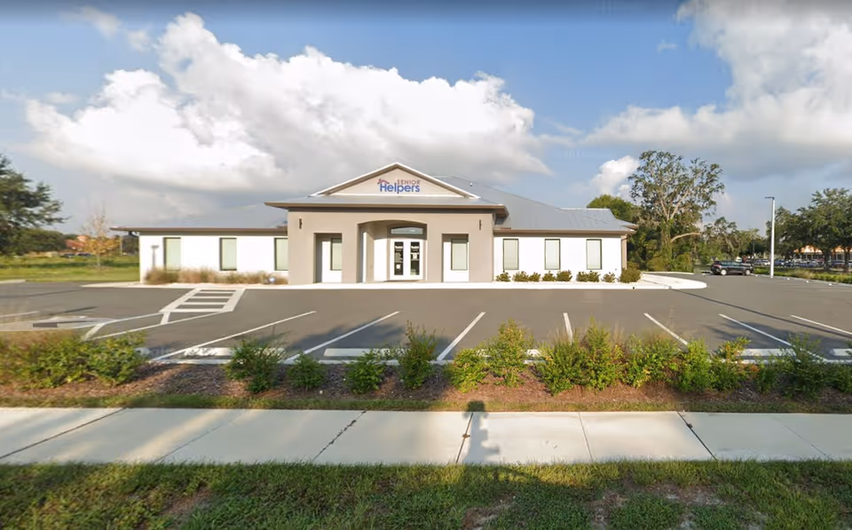 Single-story Senior Helpers facility front with parking and blue sky.