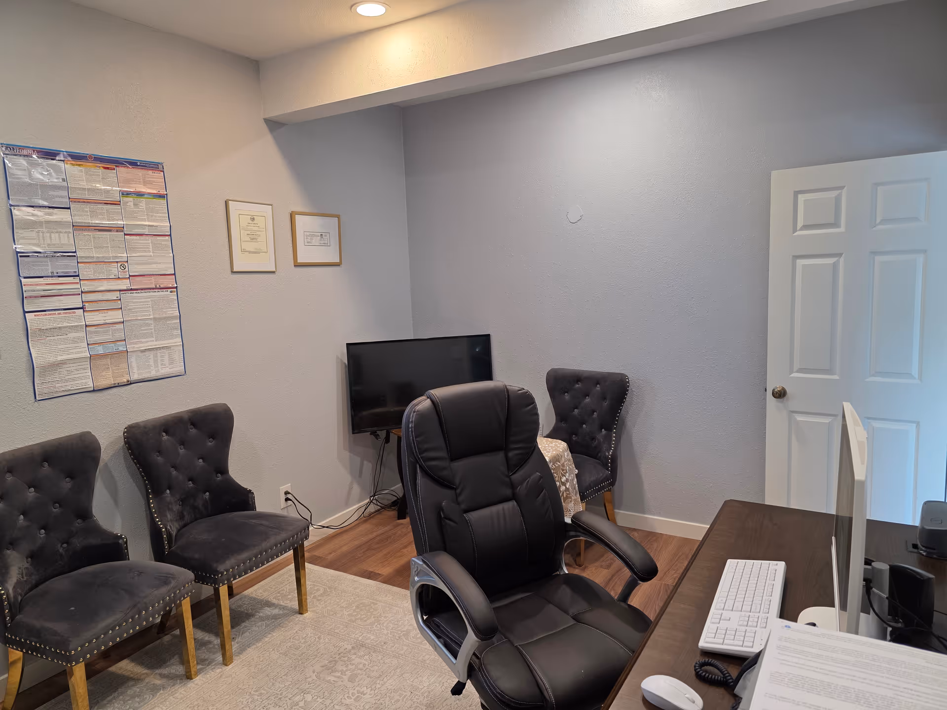 A small office in a senior care facility with desk, TV, and waiting chairs.