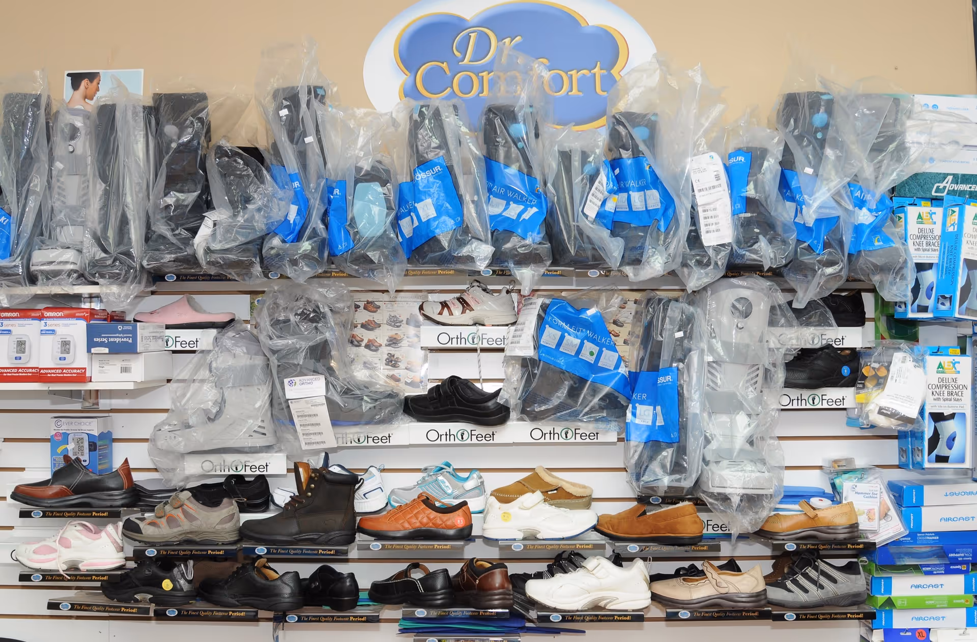 Rows of orthopedic footwear and medical devices arranged on a wall display indoors.