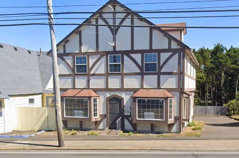 A Tudor-style two-story building with timber framing and bay windows on a street.