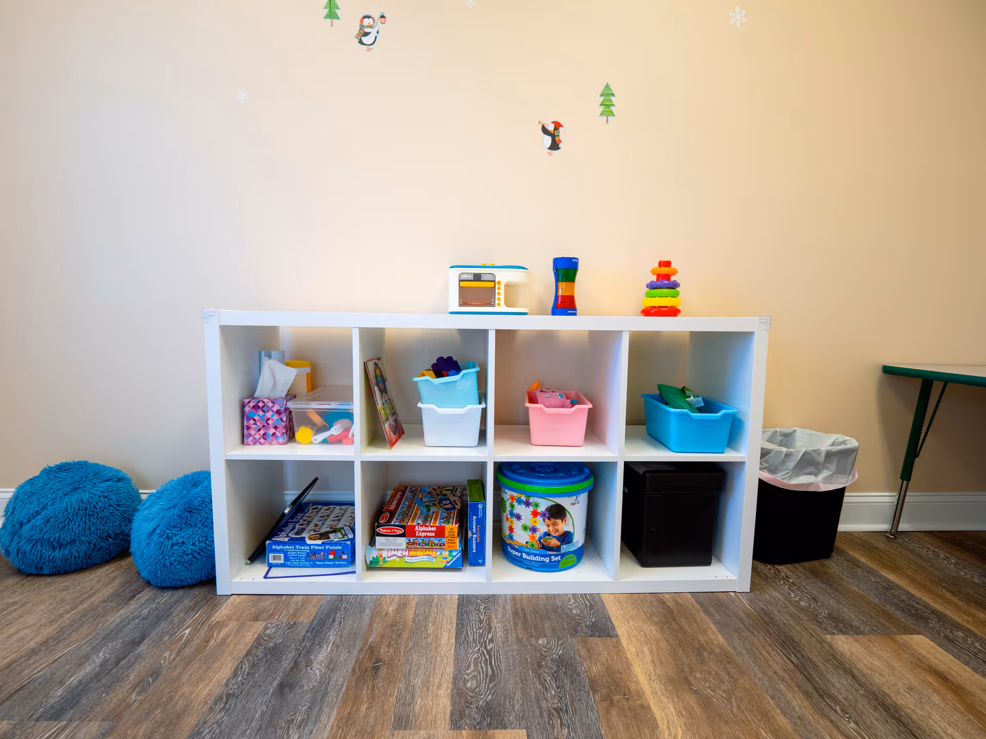 White cubby shelf filled with bins and toys in a Priorities ABA playroom.
