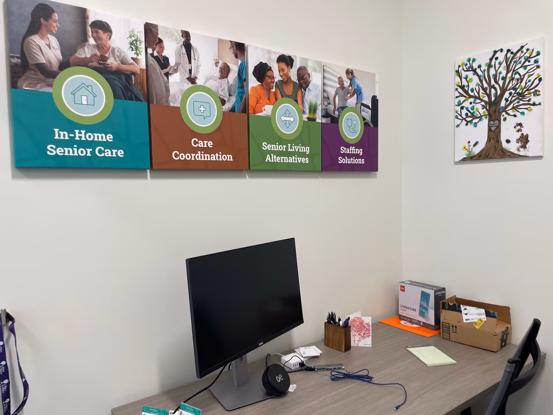Interior office area at a home care facility with a desk, monitor, and wall signage.