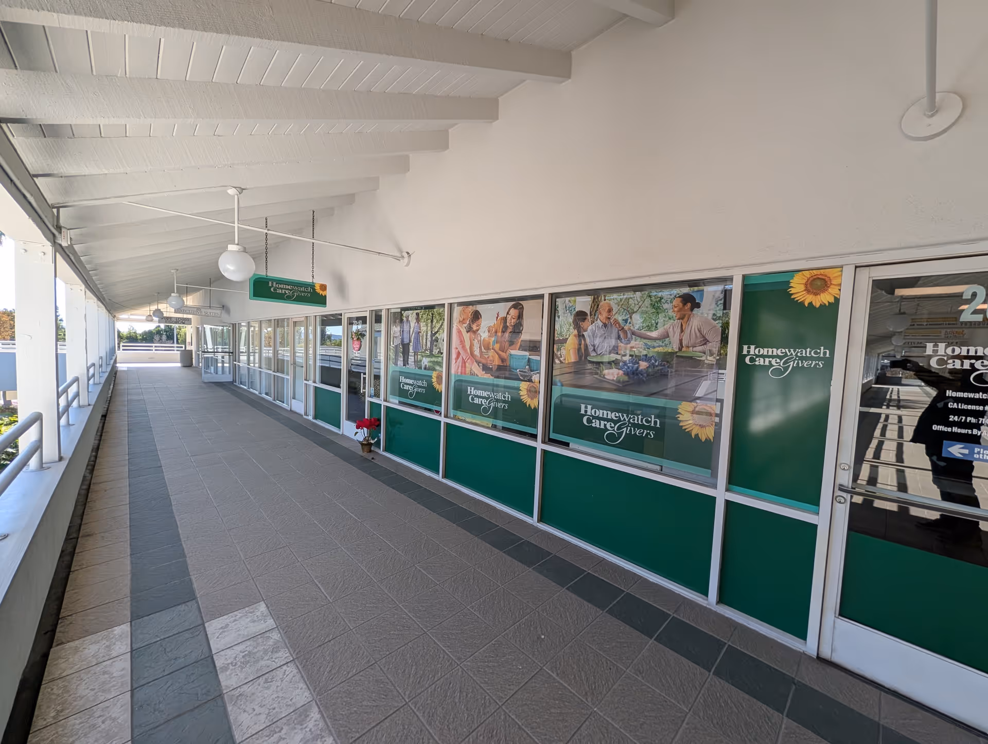 Outdoor covered walkway along Homewatch CareGivers of Yorba Linda storefronts and posters.