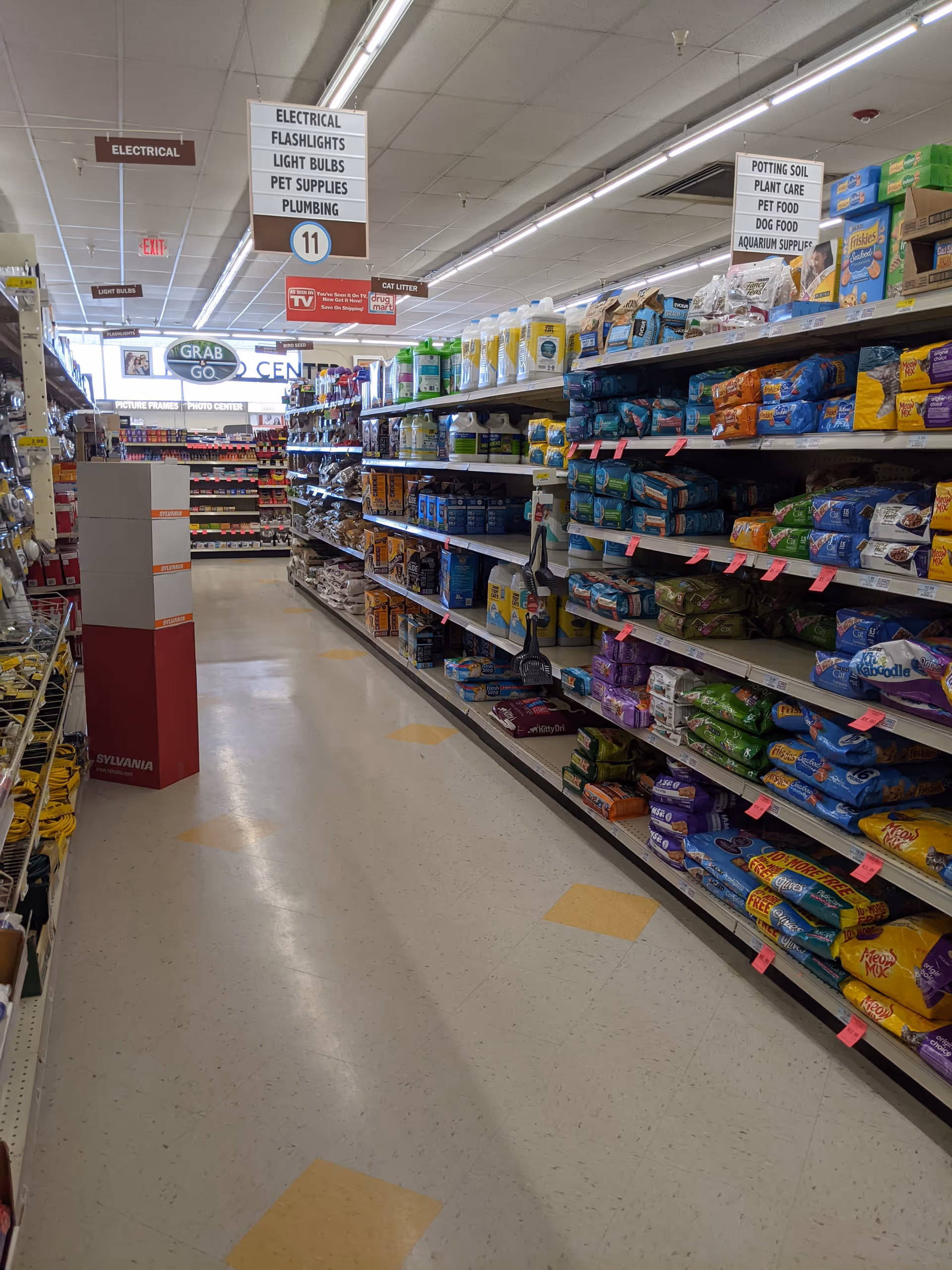 A grocery aisle with shelves of pet food and supplies inside Discount Drug Mart.