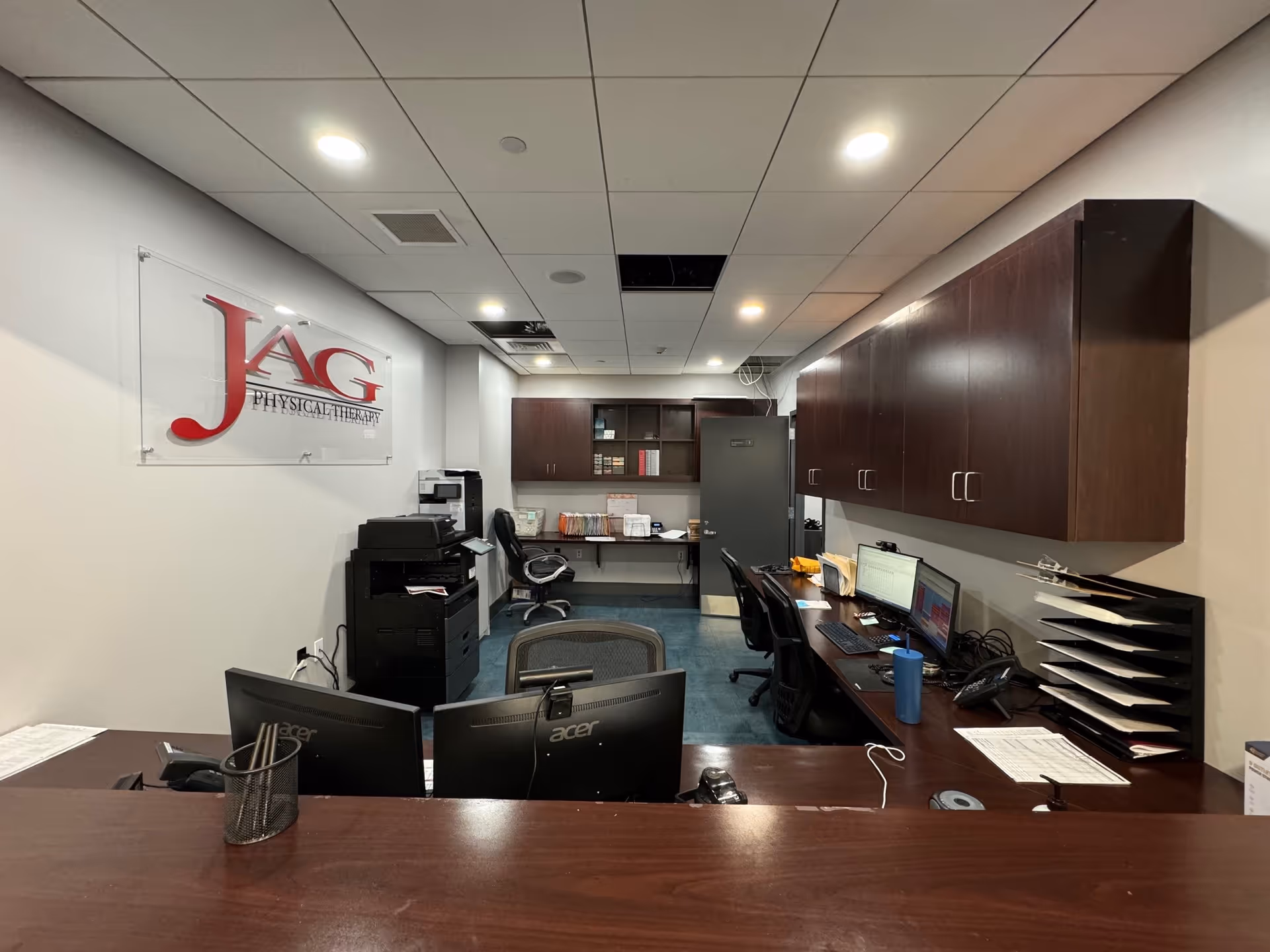 Reception area inside JAG Physical Therapy with desks, computers, and cabinets.