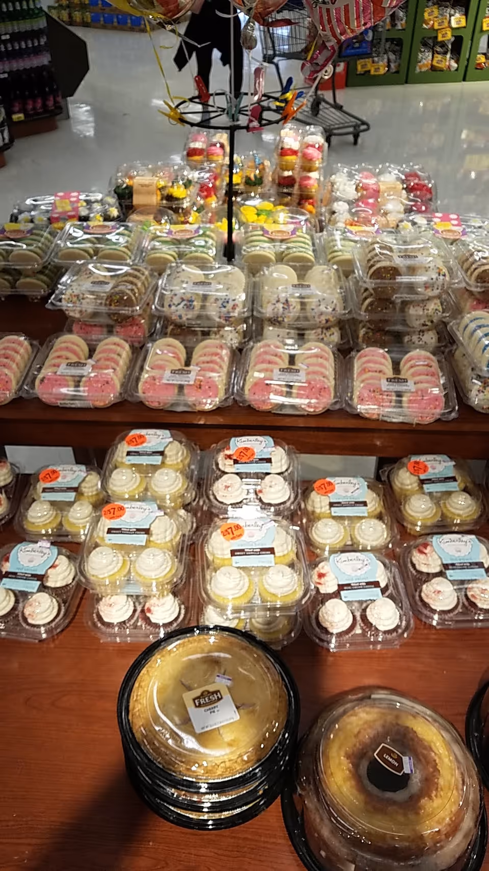 Assorted packaged desserts and cakes displayed on tables inside a Kroger Pharmacy.