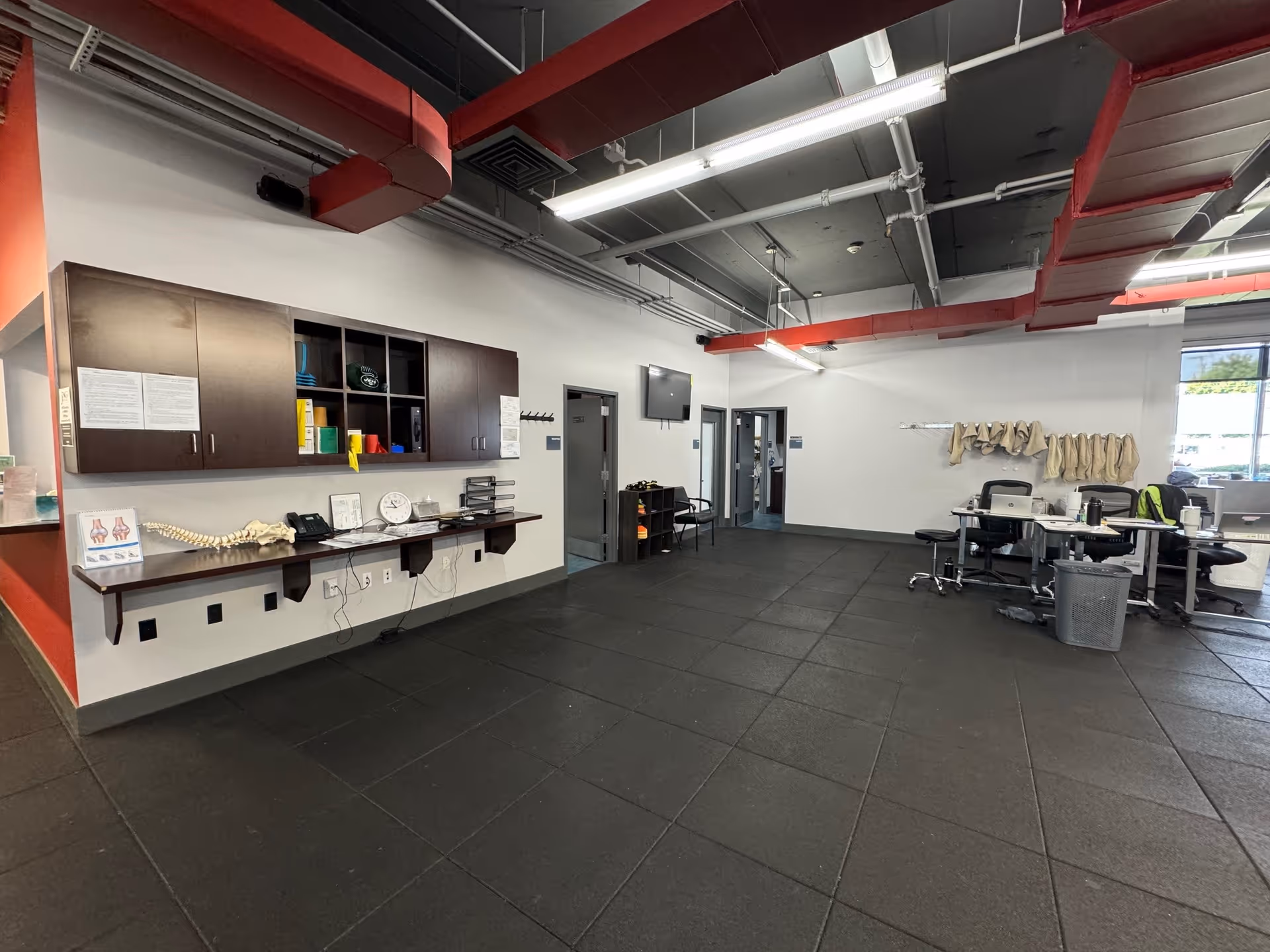Interior view of a physical therapy facility with cabinets, desks, and a workout area.