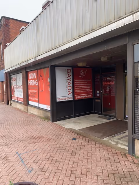 Exterior view of a BAYADA Pediatrics storefront with red hiring signs and glass doors.