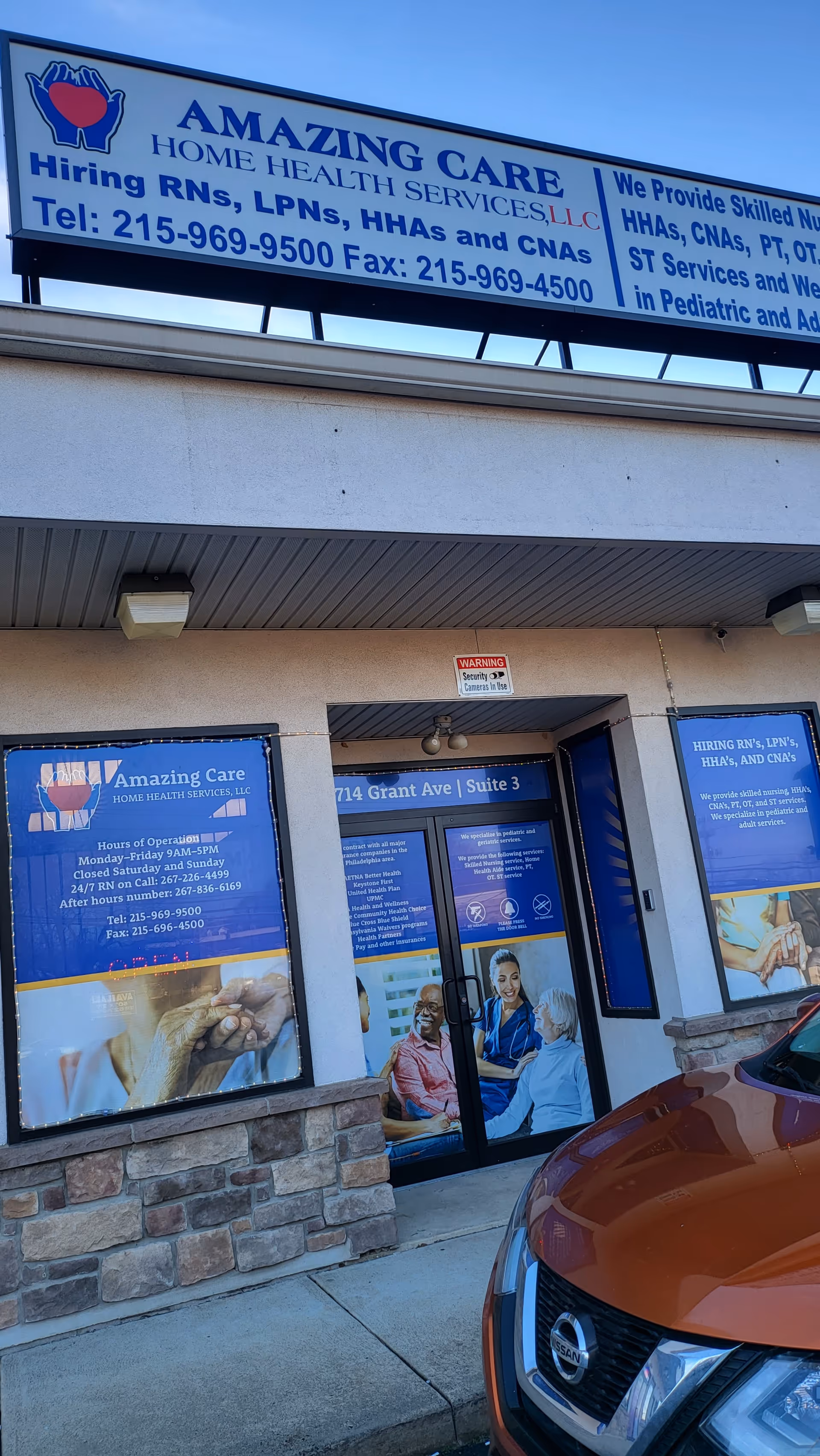 Exterior view of Amazing Care storefront with blue signage and an orange Nissan parked in front.