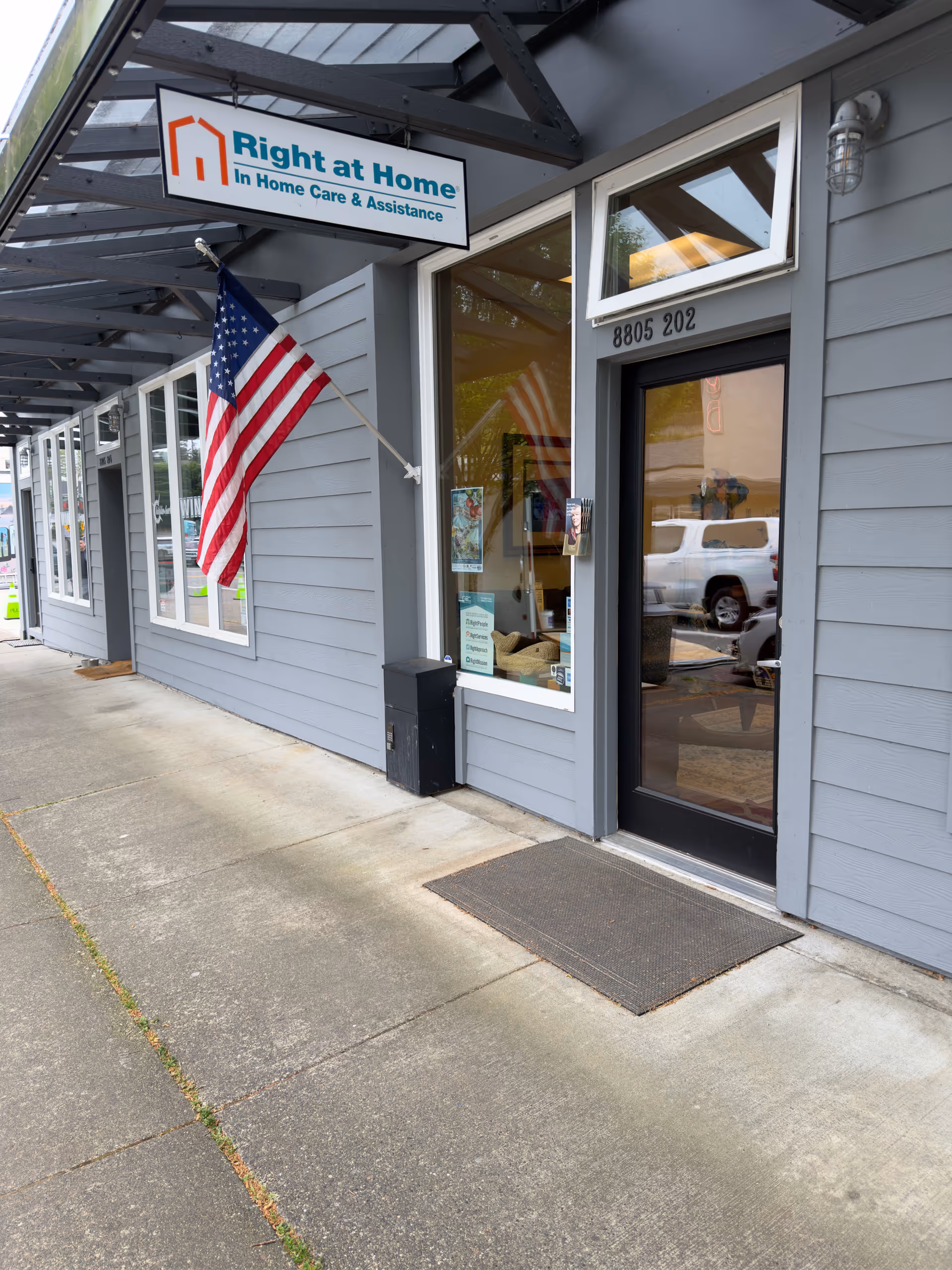 Exterior view of Right at Home facility with door, sign, and American flag.