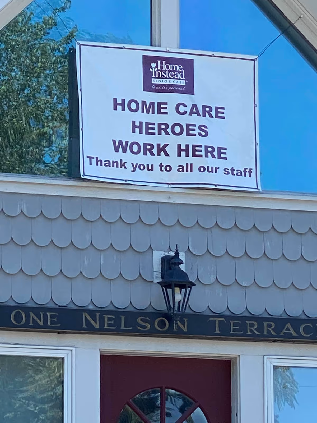 Exterior of Home Instead facility showing a large banner and One Nelson Terrace sign.