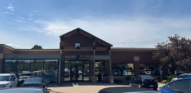 Front view of a BAYADA Home Health facility with glass entrance and parked cars.
