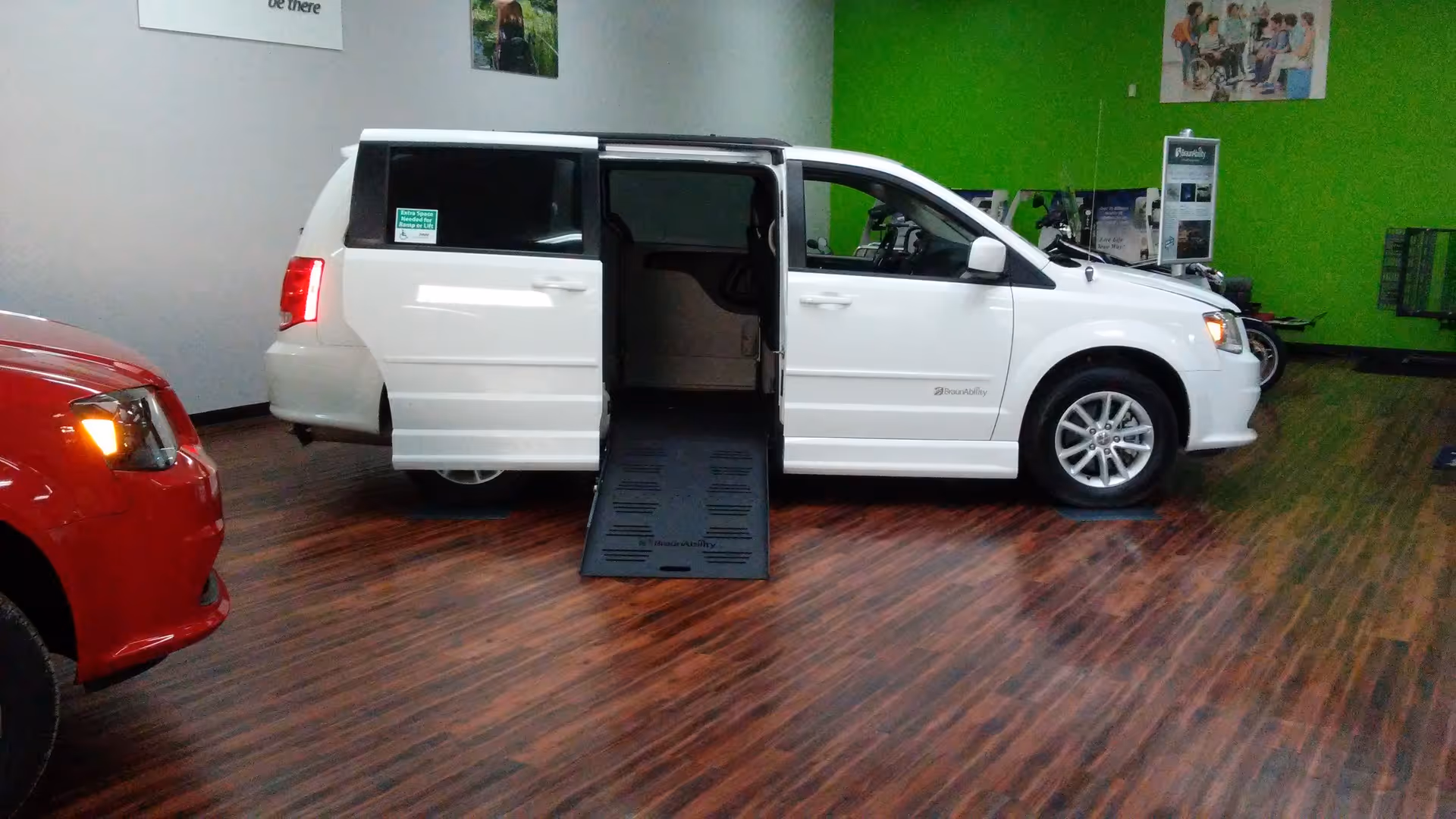 White wheelchair-accessible van with ramp extended inside showroom.