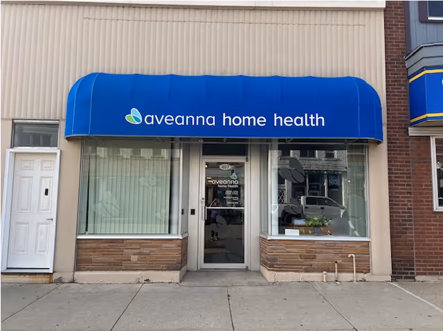 Storefront with blue awning displaying Aveanna Home Health and glass door.