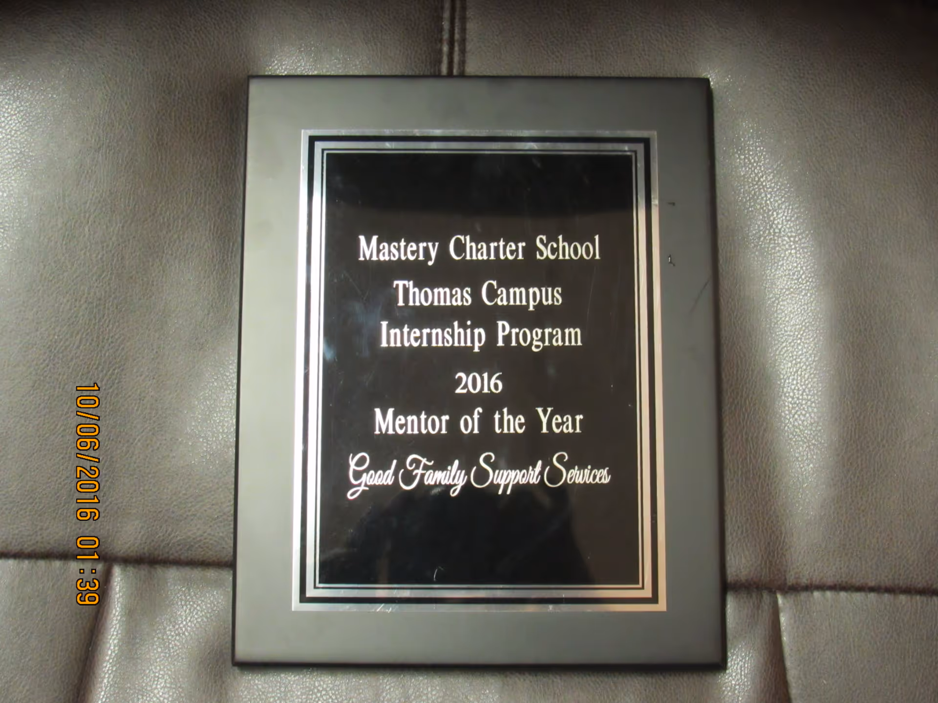 Framed plaque on a leather couch recognizing Mentor of the Year for Good Family Support Services.