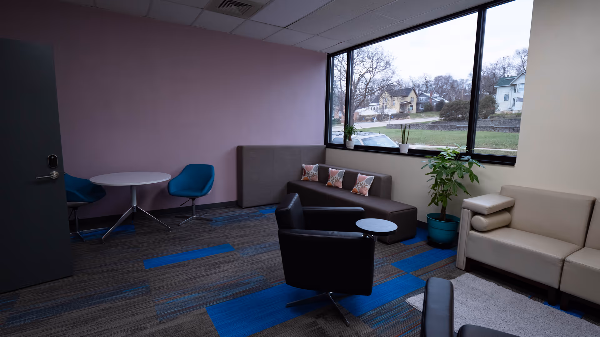 Cozy modern lounge area with sofas, chairs, tables, and a large window view.