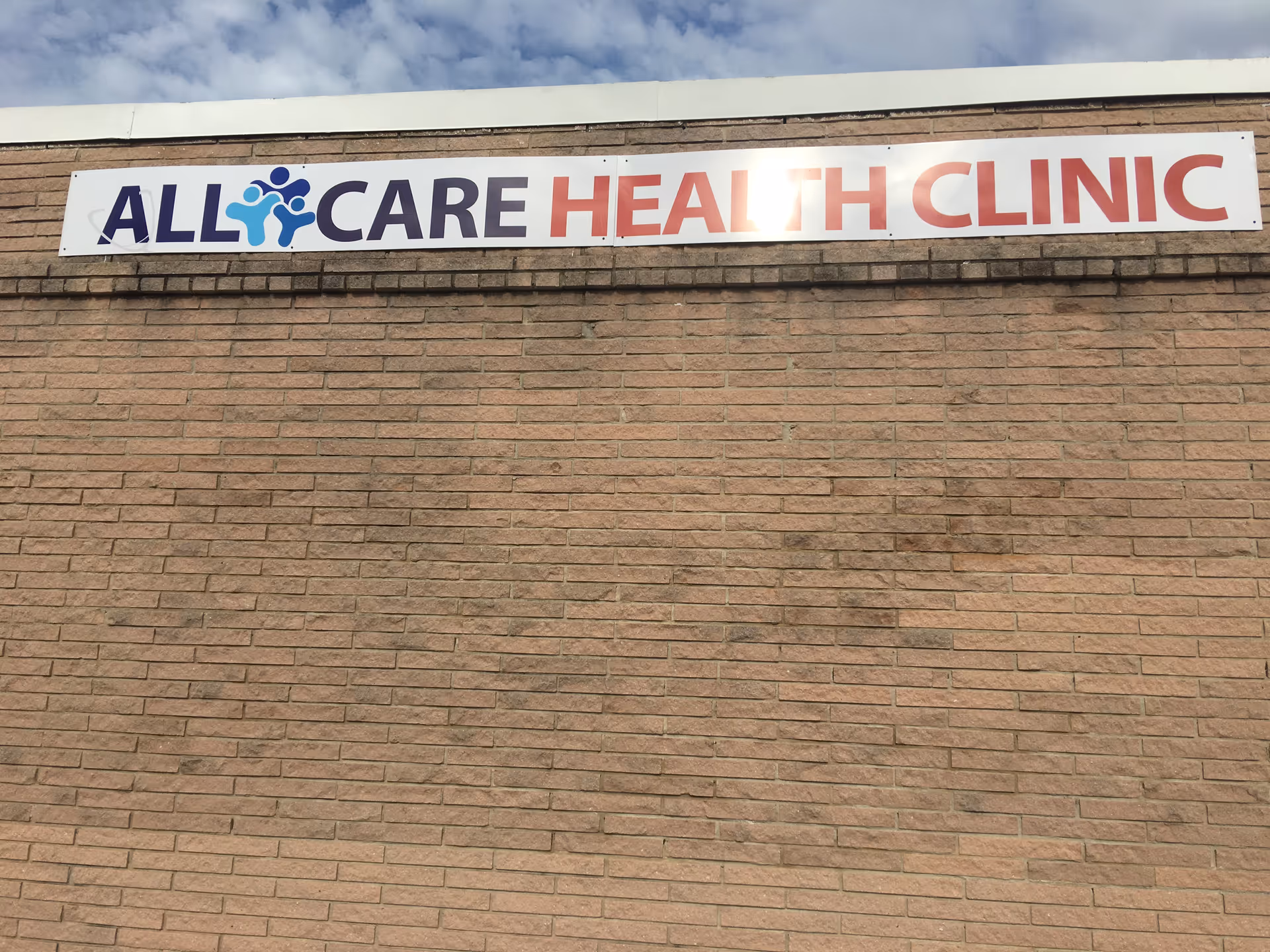 Brick exterior with a large All Care Health Clinic sign on the wall.